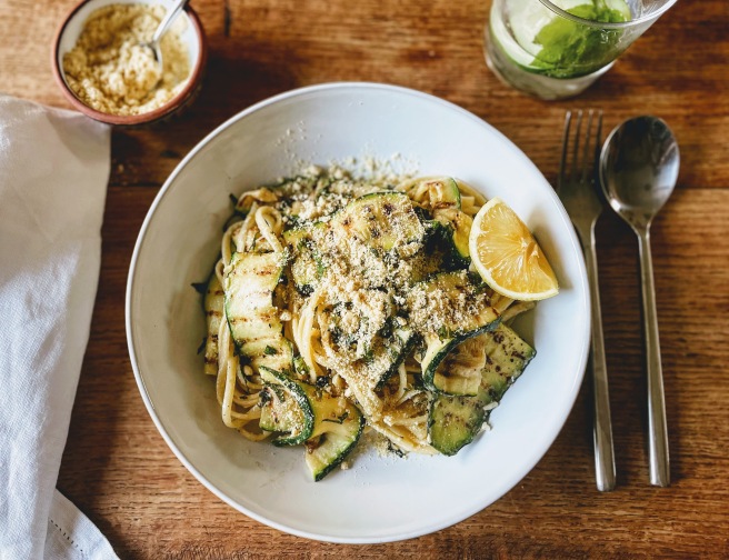 The courgette linguine seen from above. Folds of grilled courgette are mixed with threads of linguine pasta, and everything is sprinkled with cashew parmesan. 